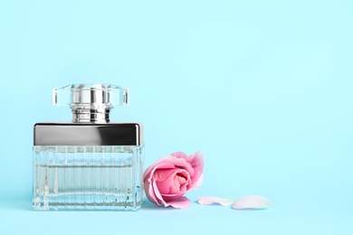Photo of Bottle of perfume and beautiful rose on light blue background. Space for text