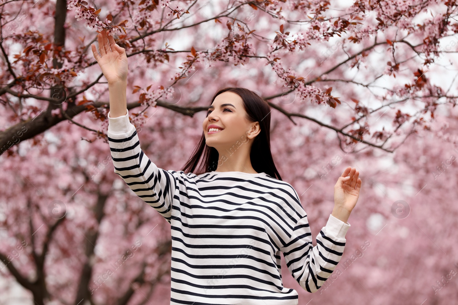 Photo of Pretty young woman near blooming tree in park. Spring look