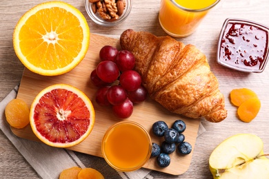 Photo of Delicious breakfast with croissant on wooden table, flat lay