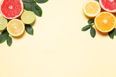 Photo of Different cut citrus fruits and leaves on beige table, flat lay. Space for text