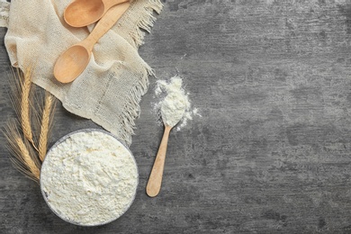 Photo of Bowl and spoon with flour on grey background, top view