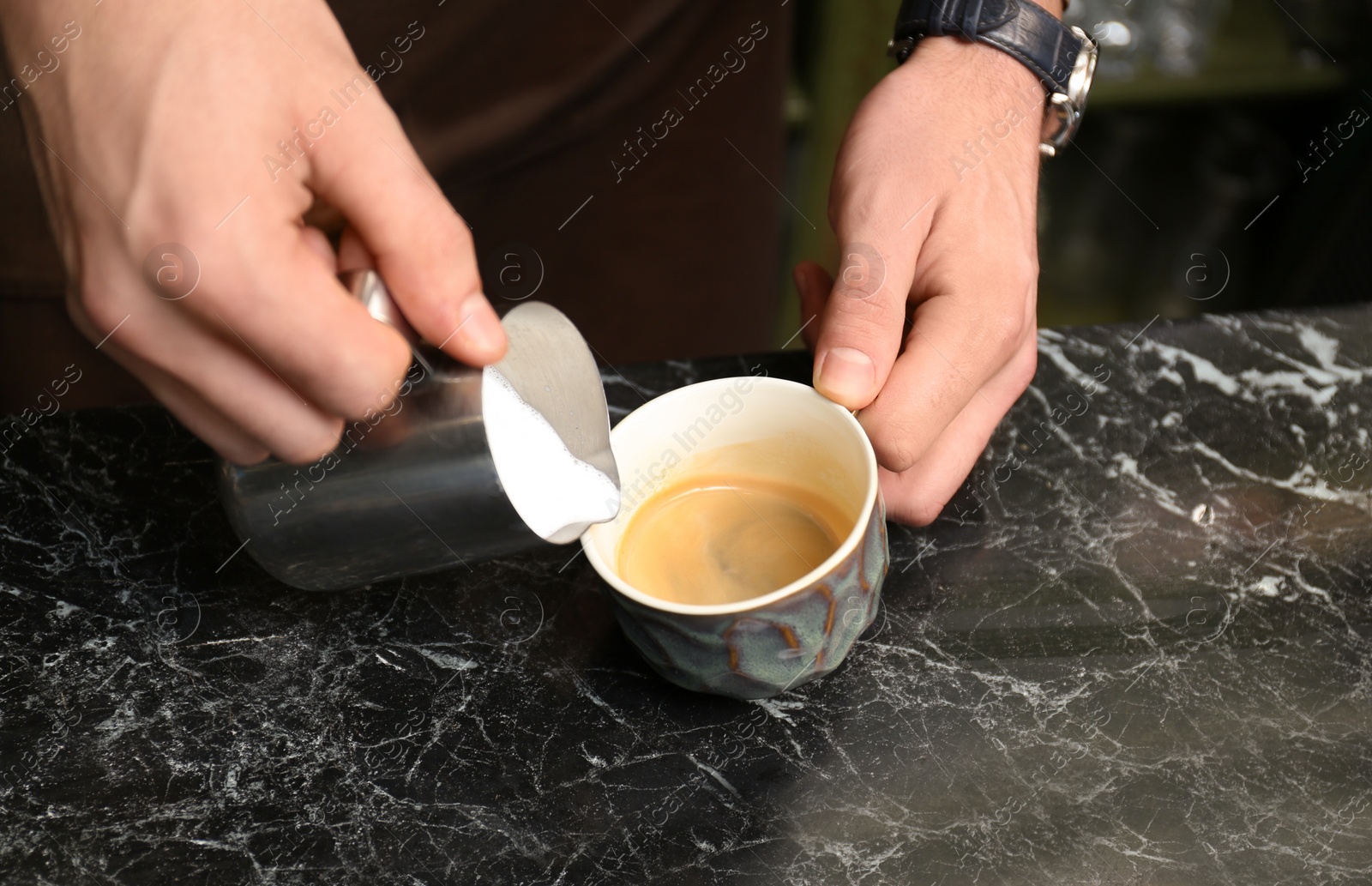 Photo of Barista adding milk to coffee at table, closeup