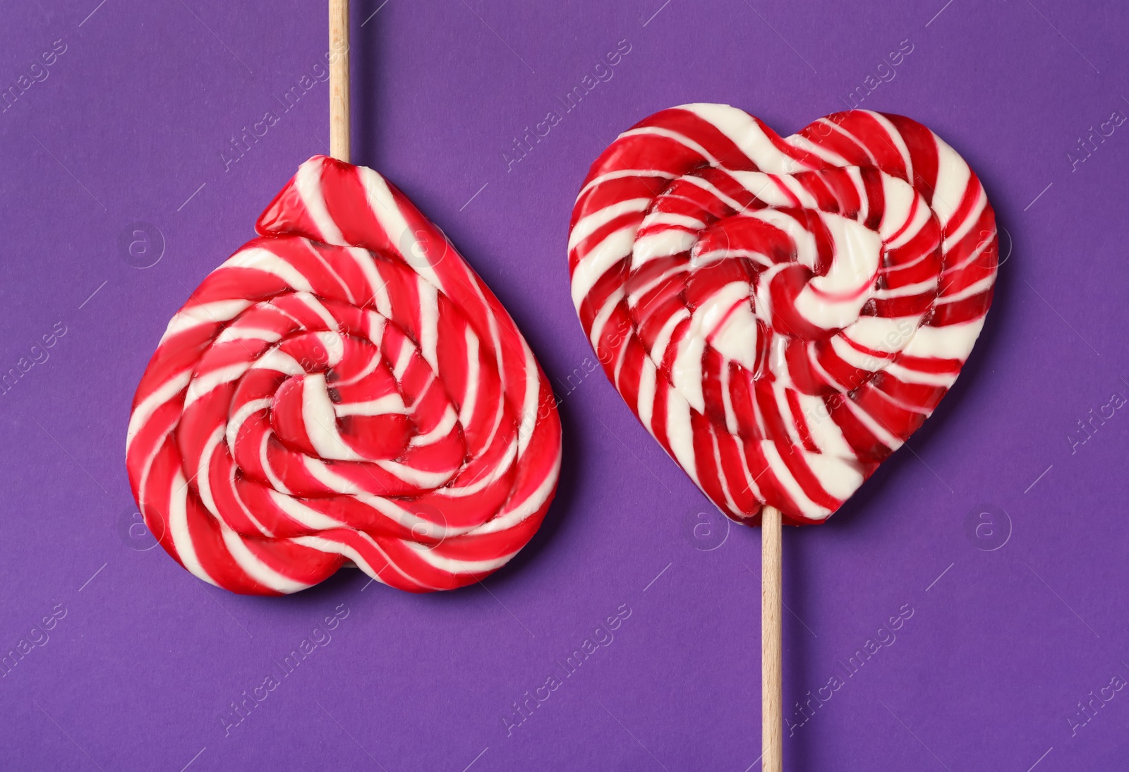 Photo of Sweet heart shaped lollipops on purple background, flat lay. Valentine's day celebration