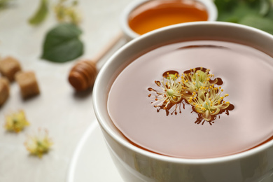 Photo of Cup of tea with linden blossom on table, closeup