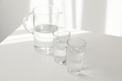 Photo of Glassware of fresh water on table against light background