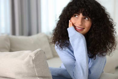 Photo of Happy young woman in stylish light blue sweater indoors, space for text