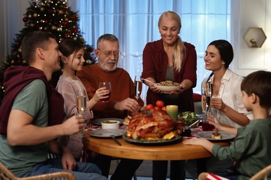 Woman with bowl of traditional Christmas Slavic dish kutia and her family during festive dinner at home
