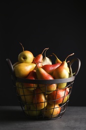 Photo of Basket with ripe pears on table against black background. Space for text