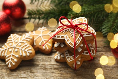 Photo of Tasty Christmas cookies with icing and festive decor on wooden table, closeup