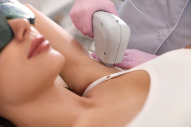 Photo of Young woman undergoing laser epilation procedure in beauty salon, closeup