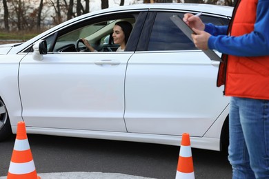 Photo of Young woman passing driving school exam at test track