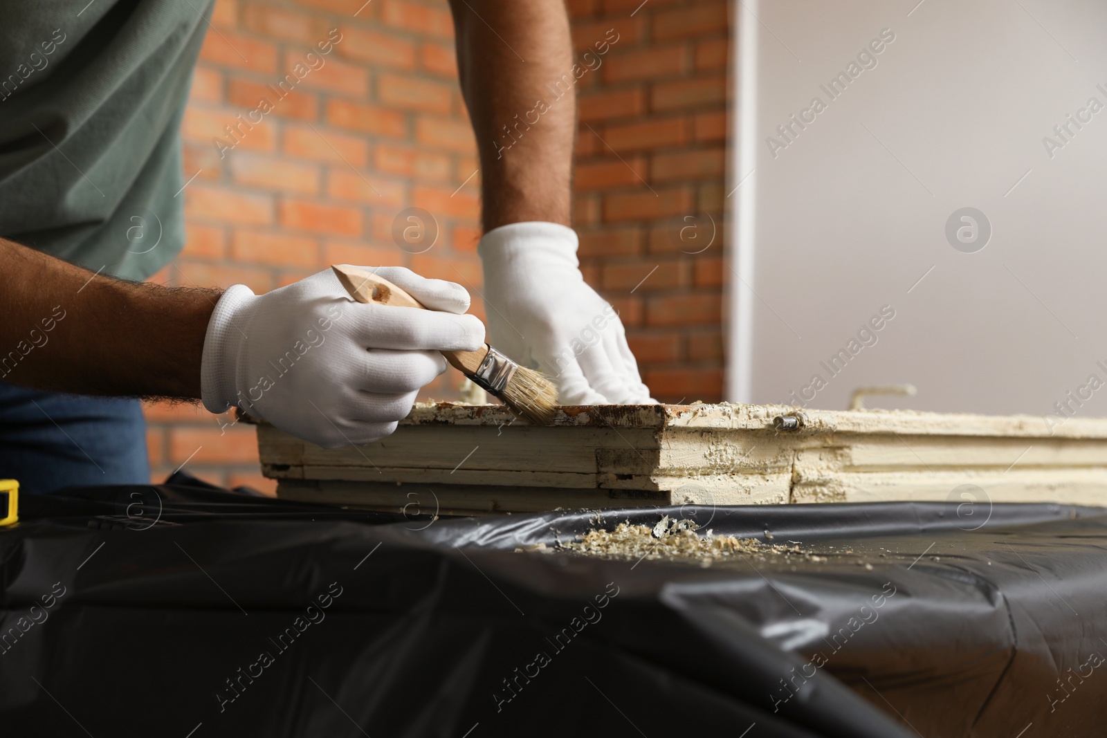 Photo of Man repairing old damaged window at table indoors, closeup