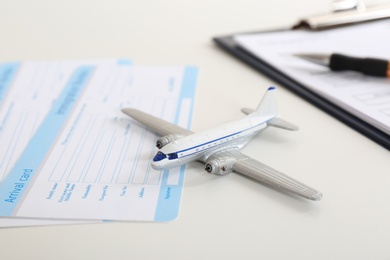 Toy plane and arrival card on white table. Travel insurance