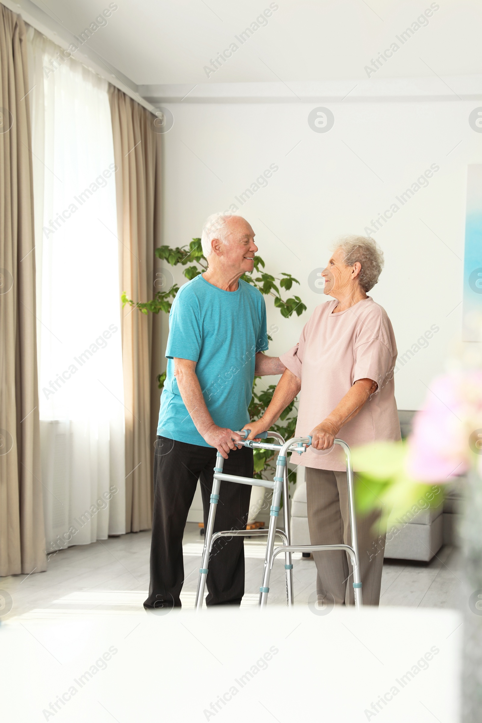 Photo of Elderly man and his wife with walking frame indoors