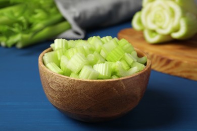 Photo of Bowl of fresh cut celery on blue wooden table, closeup