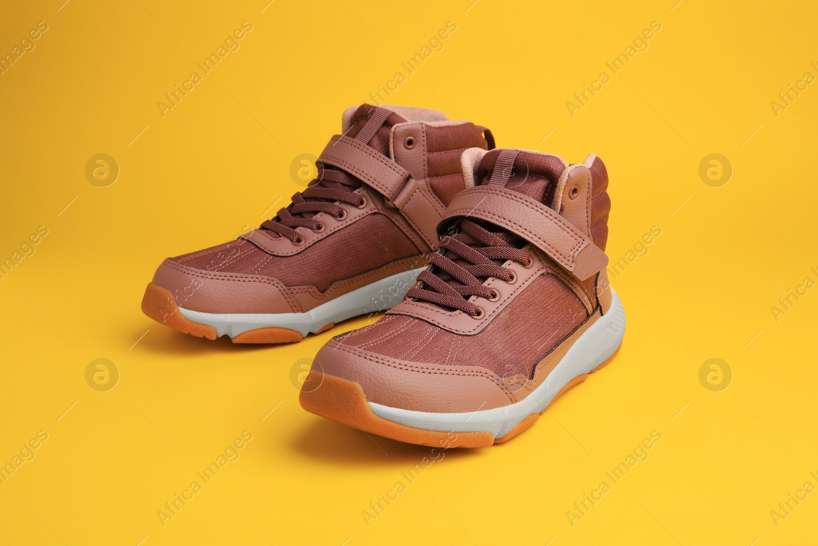 Photo of Pair of stylish kid's sneakers on yellow background