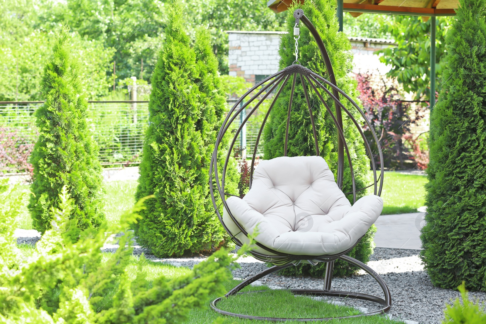 Photo of Beautiful English style garden with comfortable hanging chair on sunny day