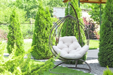 Beautiful English style garden with comfortable hanging chair on sunny day