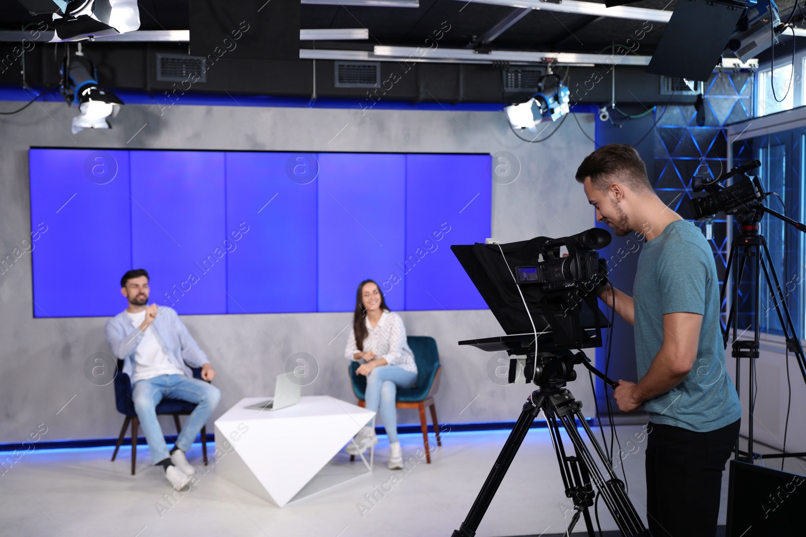 Photo of Presenters and video camera operator working in studio. News broadcasting