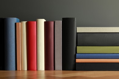 Photo of Many different books on wooden table near black wall