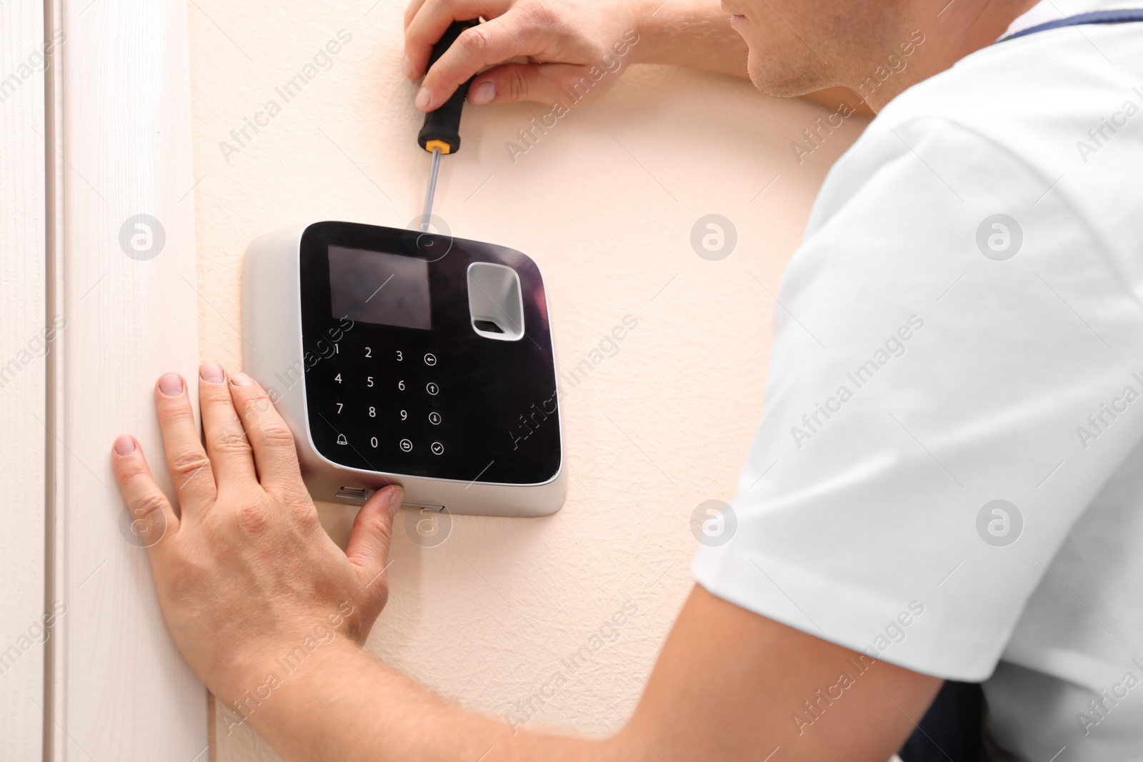 Photo of Male technician installing security alarm system indoors, closeup