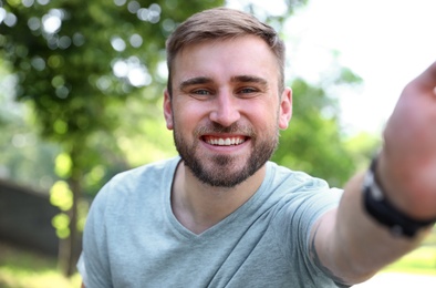 Photo of Happy young man taking selfie in park