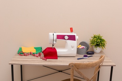 Photo of Modern sewing machine on table against light background