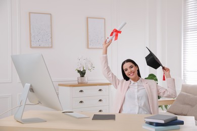 Photo of Happy student with graduation hat and diploma at workplace in office