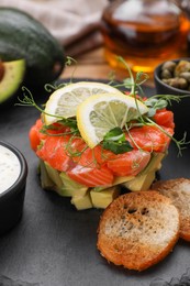 Photo of Delicious salmon tartare served with avocado and croutons on table, closeup