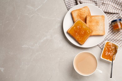 Toasts, orange jam and cup of coffee served on light marble table, flat lay. Space for text