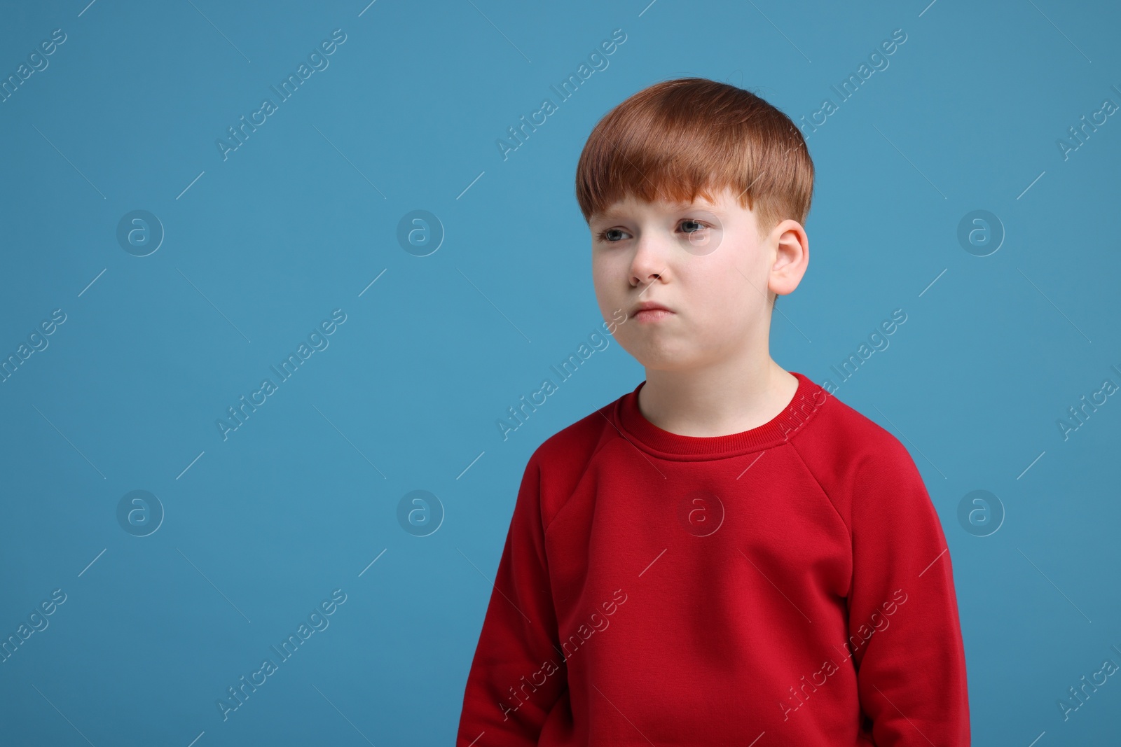 Photo of Portrait of sad little boy on light blue background, space for text