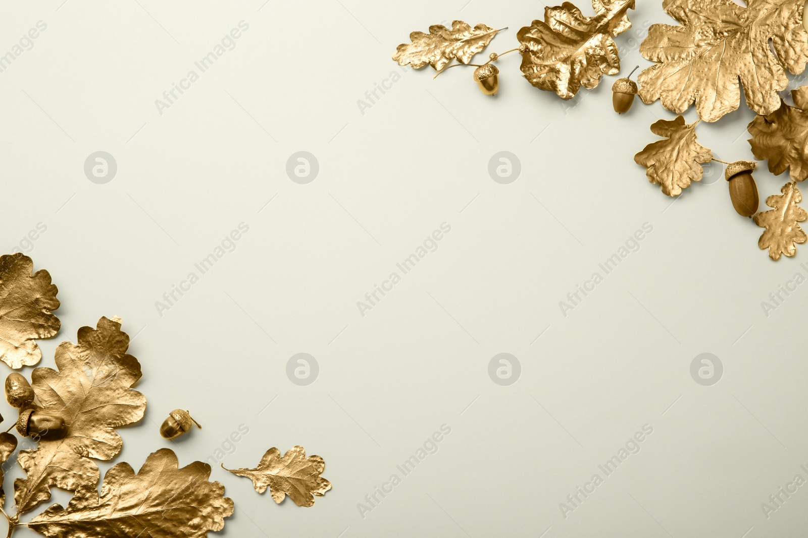 Photo of Golden oak leaves and acorns on beige background, flat lay with space for text. Autumn decor