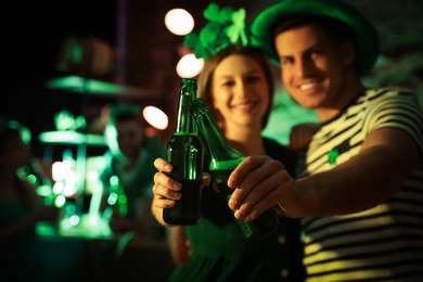 Photo of Couple with beer celebrating St Patrick's day in pub, focus on hands
