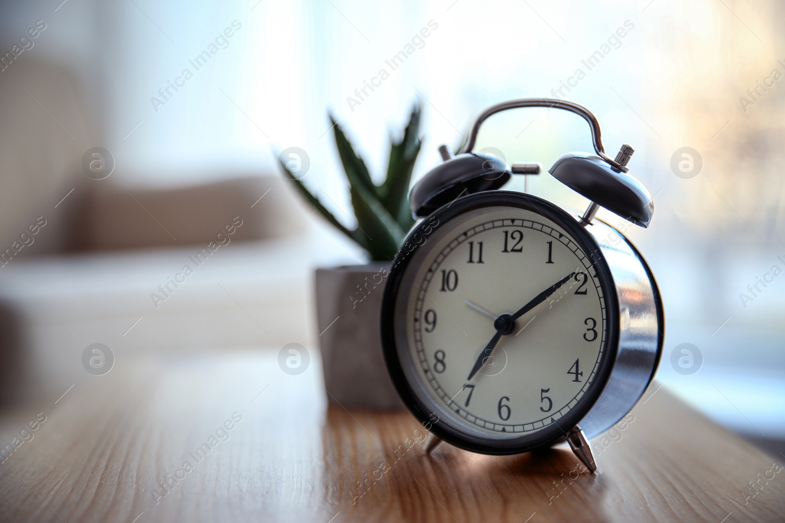 Photo of Alarm clock on wooden table at home. Morning time