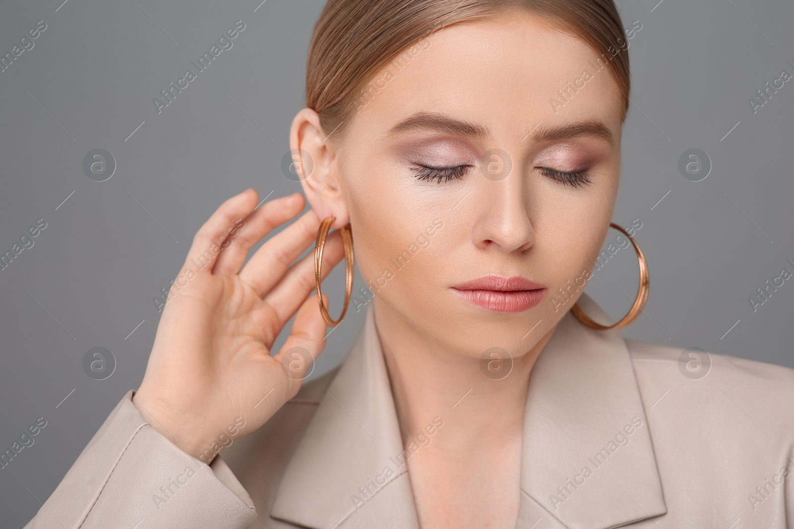 Photo of Beautiful young woman with elegant earrings on gray background