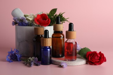 Aromatherapy. Different essential oils, flowers, mortar and pestle on pink background