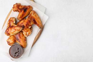 Photo of Board with marinade and chicken wings on light table, top view. Space for text