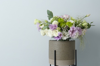 Bouquet with beautiful Eustoma flowers in ceramic cachepot on light background. Space for text