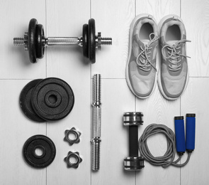 Photo of Gym equipment and shoes on wooden floor, flat lay