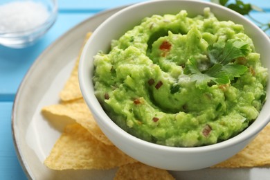 Photo of Delicious guacamole served with nachos chips on table, closeup