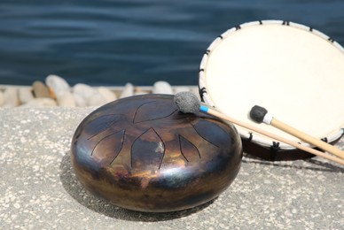 Photo of Different drums, soft mallet and drumstick near sea. Percussion musical instruments