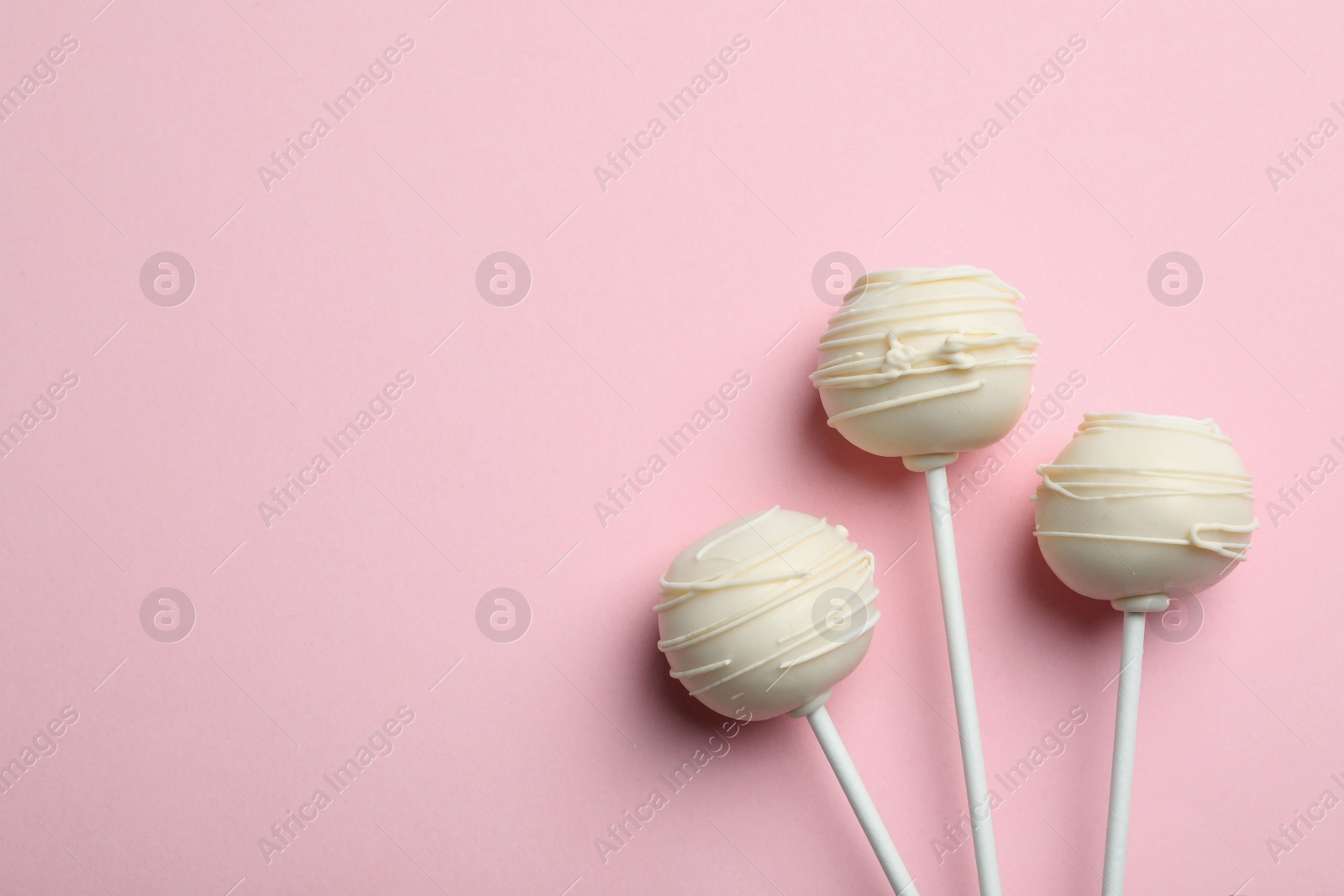 Photo of Sweet cake pops on pink background, flat lay. Space for text