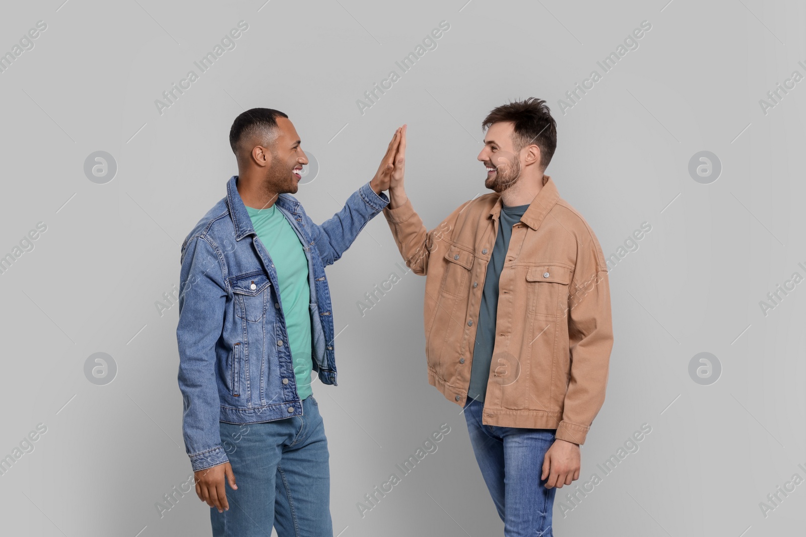 Photo of Men giving high five on grey background