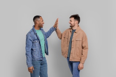 Men giving high five on grey background