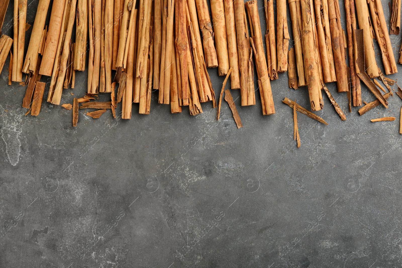 Photo of Aromatic cinnamon sticks on grey table, flat lay. Space for text