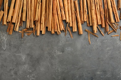 Aromatic cinnamon sticks on grey table, flat lay. Space for text