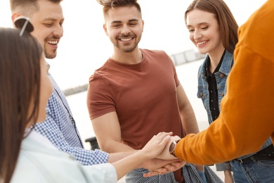 Photo of Group of happy people holding hands together, outdoors