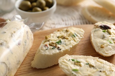 Photo of Tasty butter with olives, green onion and bread on table, closeup