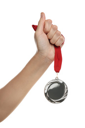 Woman holding silver medal on white background, closeup. Space for design