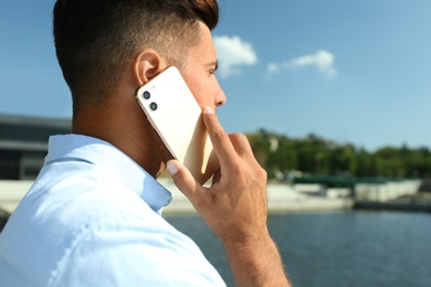 Photo of Man talking on modern mobile phone near river